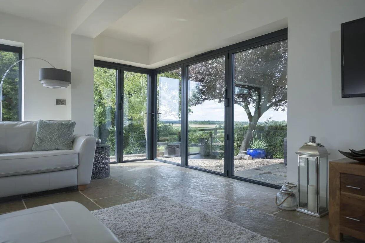 Anthracite aluminium glazed doors wrapping the corner of a living room, looking out over a garden