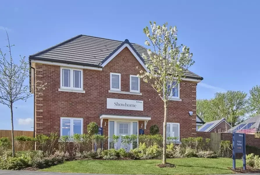 Red brick Bellway showhome with white windows and a white front door on a new-build development