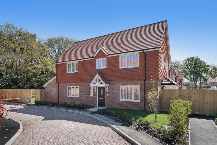 New-build red brick house with a tile-hung upper floor, white windows and a black front door