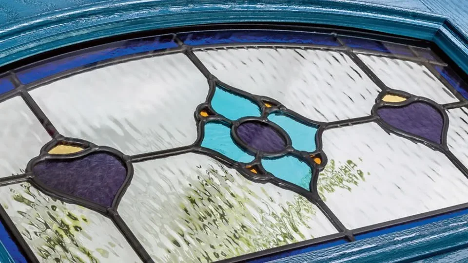 Close-up of decorative leaded door glass with purple and turquoise panes set in textured clear glass