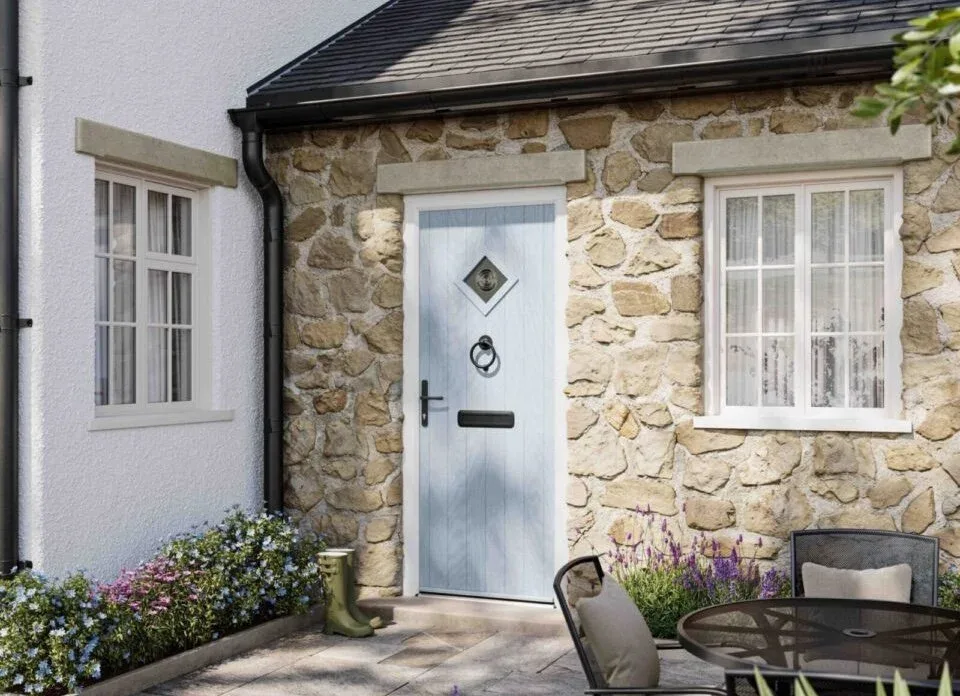 Pale blue composite front door with a diamond glass panel on a stone cottage beside white windows