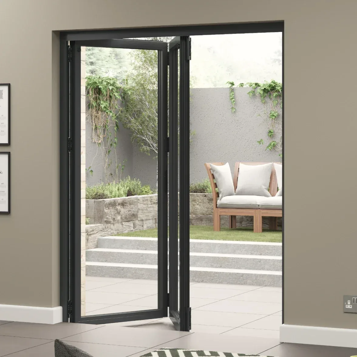 Dark grey bi-fold doors folded open from a room onto a garden patio with steps and an outdoor sofa