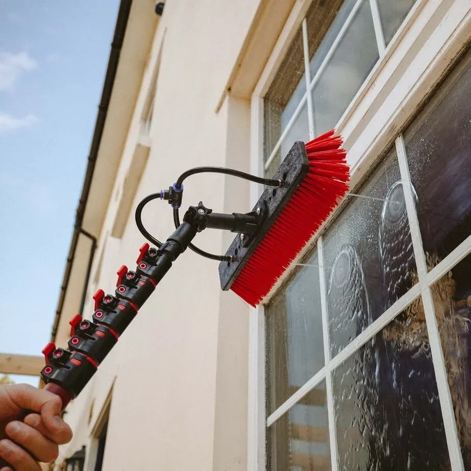 Water-fed pole brush cleaning the glass of a white-framed window
