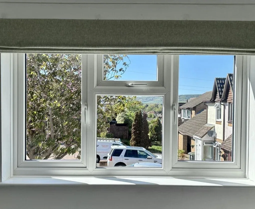 White casement windows with a top opener, seen from inside looking out onto a residential street